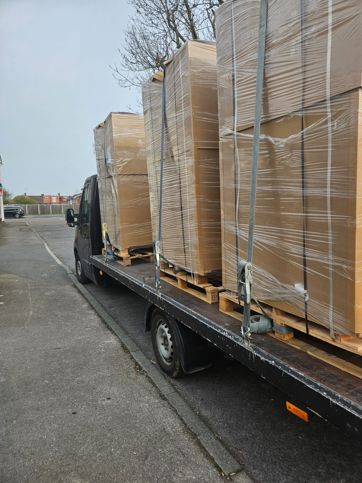 Flatbed loaded with wrapped pallets, ratchet-strapped for transit